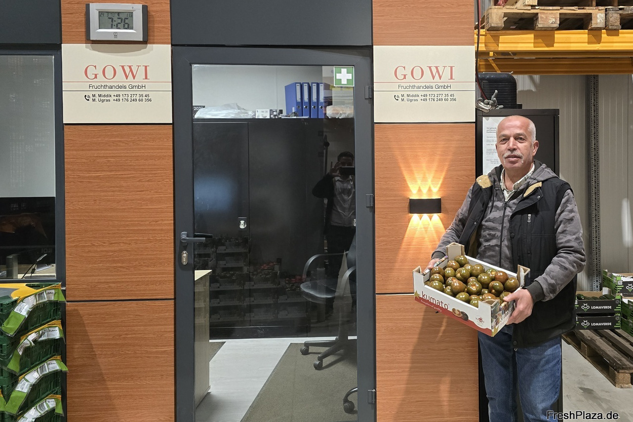 Mehmet Middik hält eine Steige Obst vor dem Büroeingang mit GOWI-Schild in der Lagerhalle am Josef-Linden-Weg